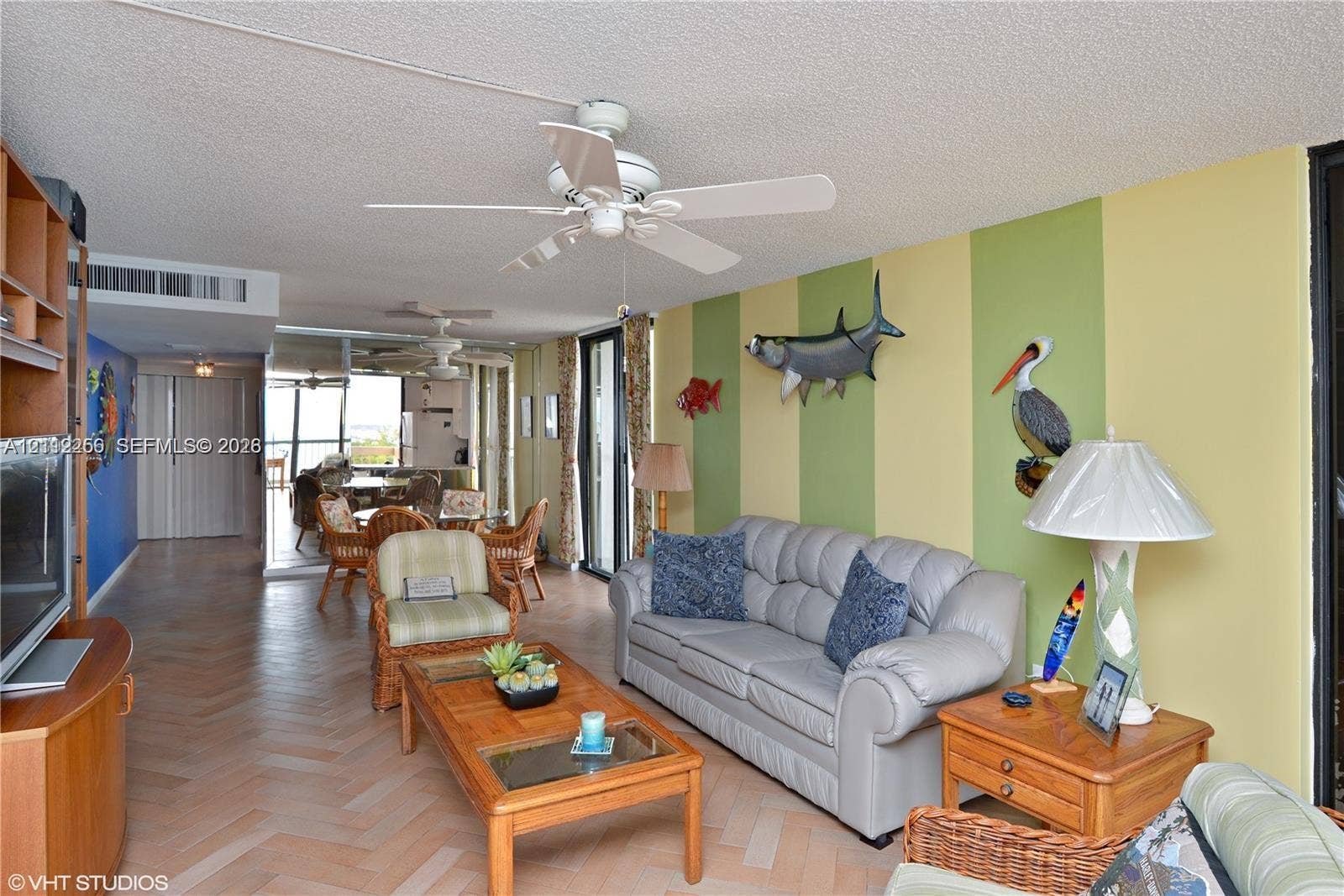 9900 S Ocean Drive, #601, Jensen Beach, FL 34957 Herringbone-patterned wood-finish flooring, ceiling-mounted paddle fans, and floor-to-ceiling glass sliding doors