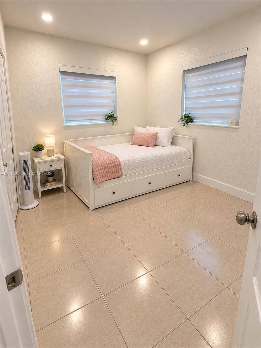 Neutral-toned tile flooring, recessed ceiling lighting, and dual windows with installed roller shades