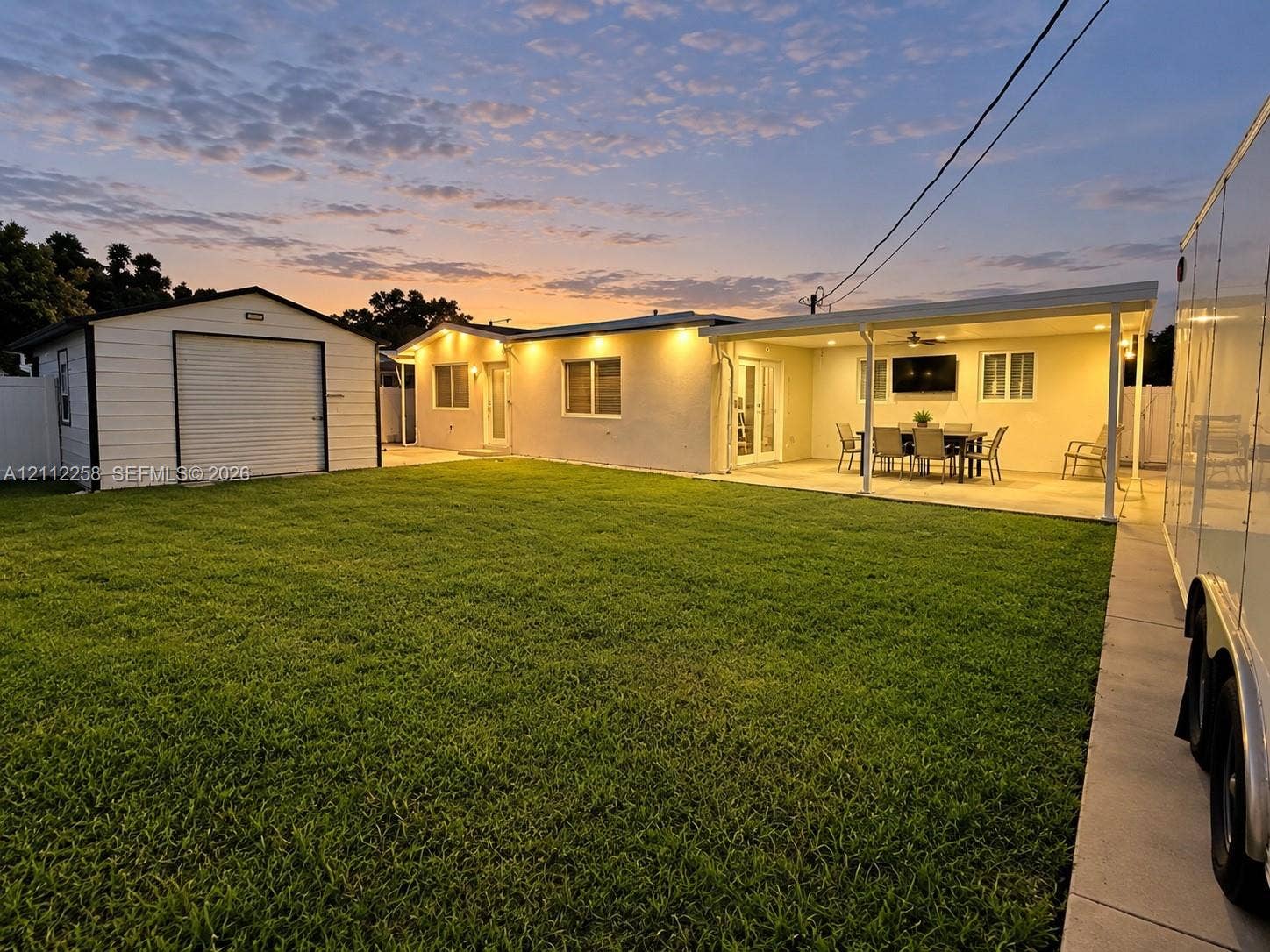 Spacious backyard featuring a manicured lawn, detached storage shed, and a covered concrete patio