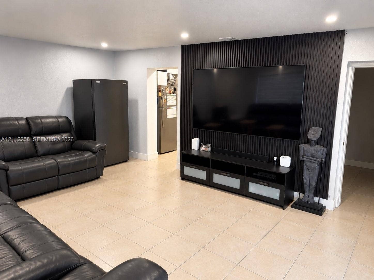 Textured black vertical-slat accent wall, tile flooring, and recessed ceiling lighting
