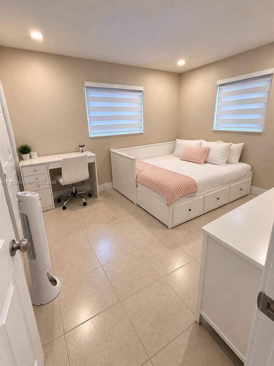 Neutral-toned interior featuring oversized tile flooring, recessed lighting, and dual windows equipped with zebra-style blinds