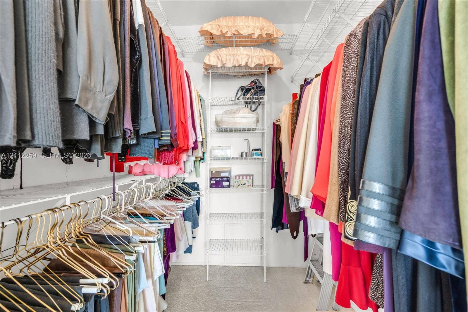 Walk-in closet featuring multi-tiered white wire shelving and built-in hanging rods