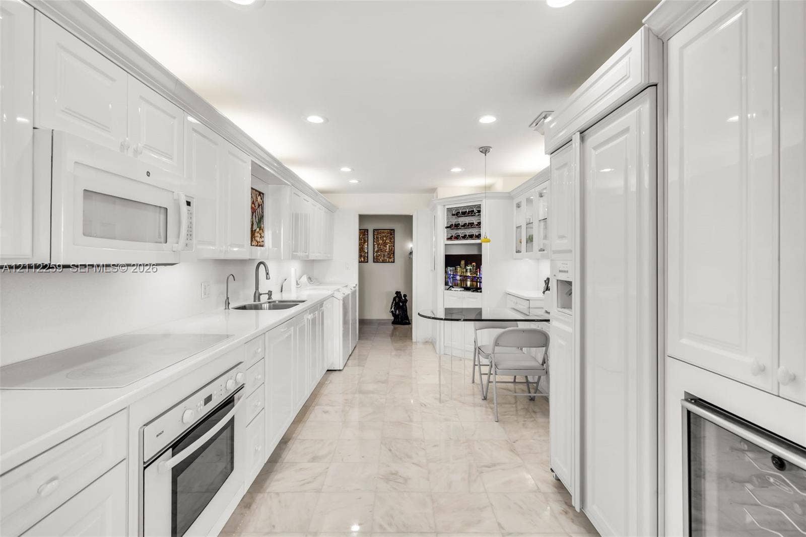 Kitchen featuring high-gloss white cabinetry, stone flooring, built-in panel-ready refrigerator, stainless steel oven, and integrated wine storage