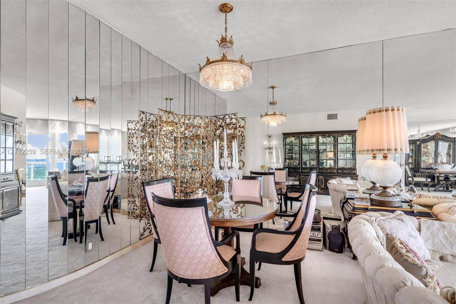 Floor-to-ceiling mirrored wall paneling, crystal tiered chandelier, and built-in glass-front cabinetry