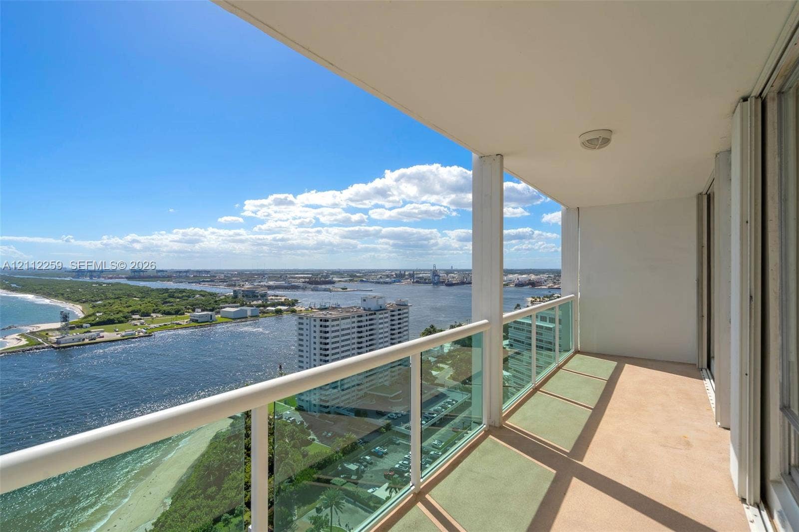Private balcony featuring a glass panel railing and panoramic waterfront and coastal scenery