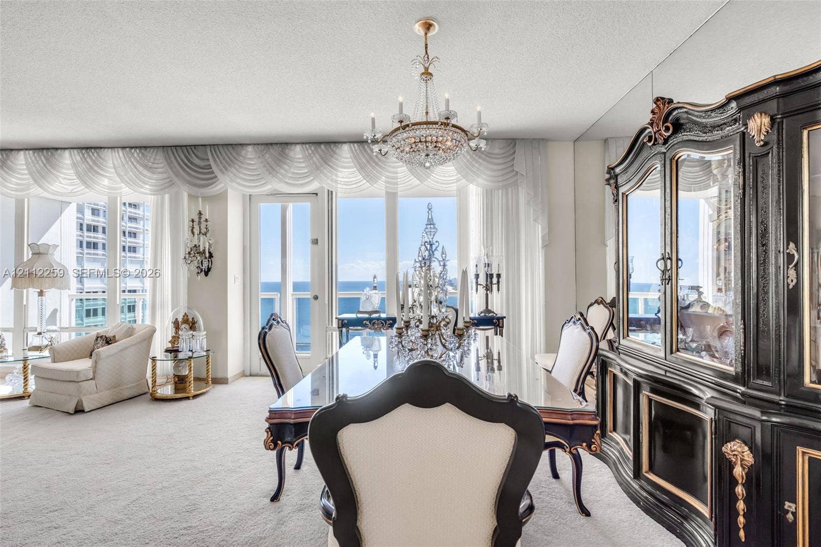 Floor-to-ceiling windows, crystal chandelier, mirrored wall paneling, and a glass-paneled door
