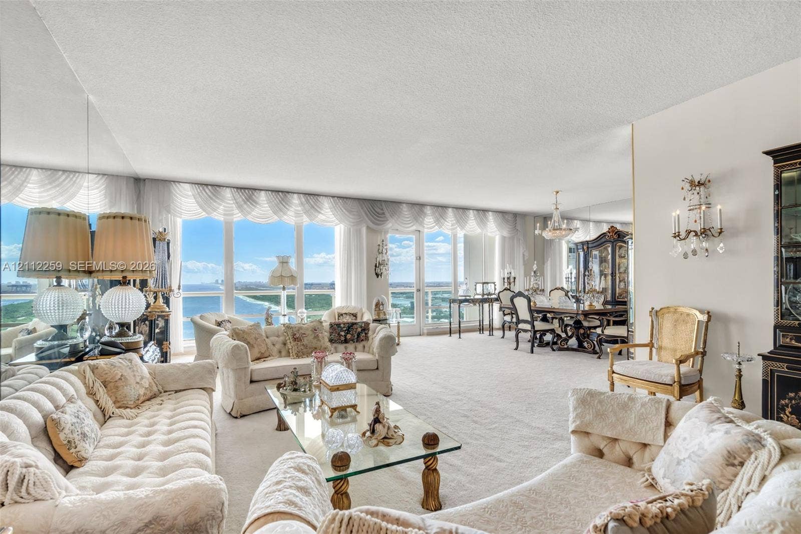 Floor-to-ceiling windows, mirrored wall accents, wall-mounted decorative sconces, and neutral carpeting