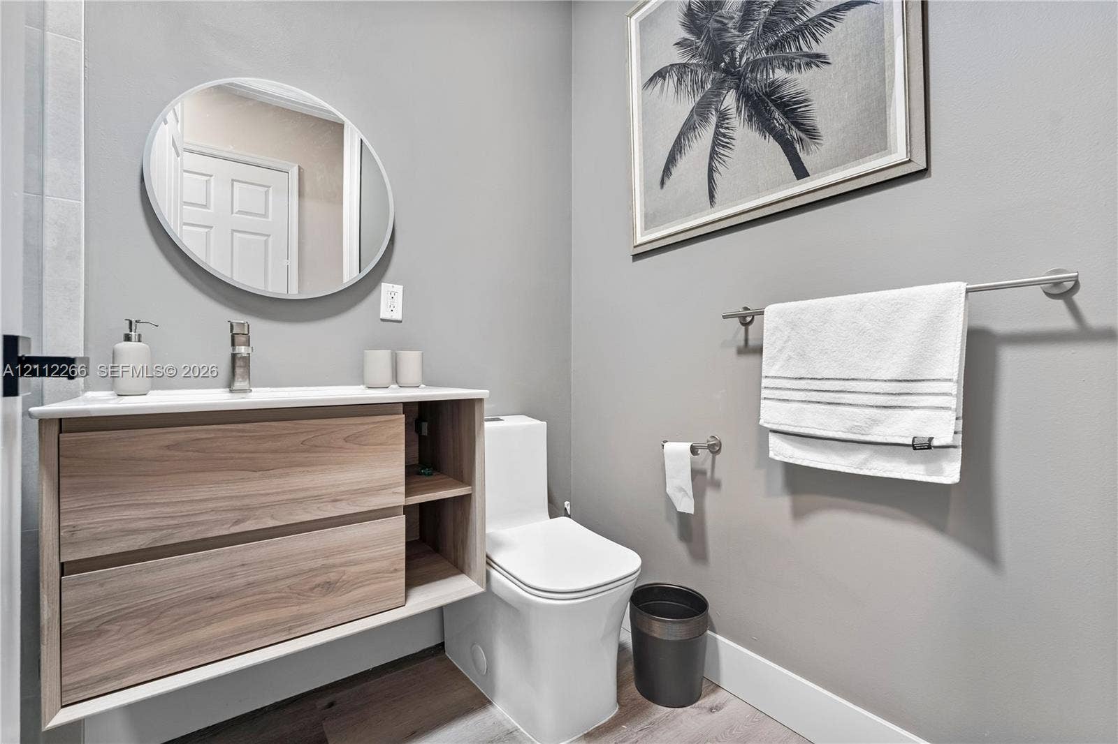 Floating wood-finish vanity with integrated shelving, white rectangular vessel sink, brushed nickel faucet, and oval wall-mounted mirror