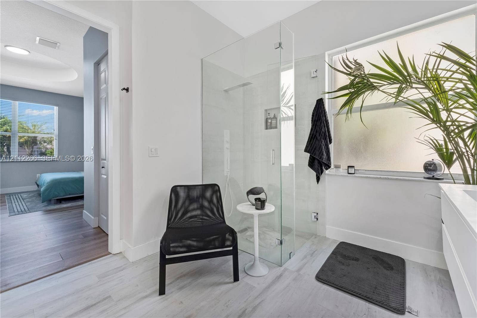 Walk-in glass shower with built-in recessed shelving, light-toned tiled flooring, and expansive horizontal window with frosted glass