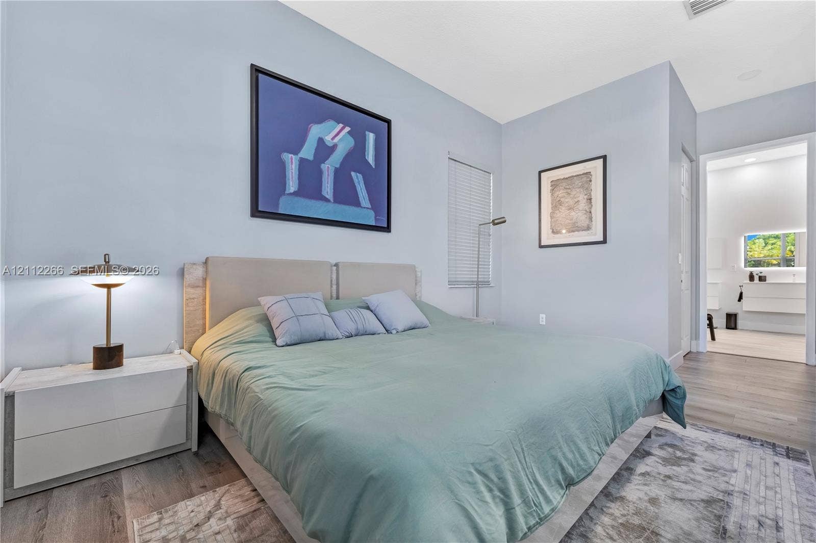 Neutral-toned room with wood-finish flooring, horizontal blinds, and a smooth wall finish