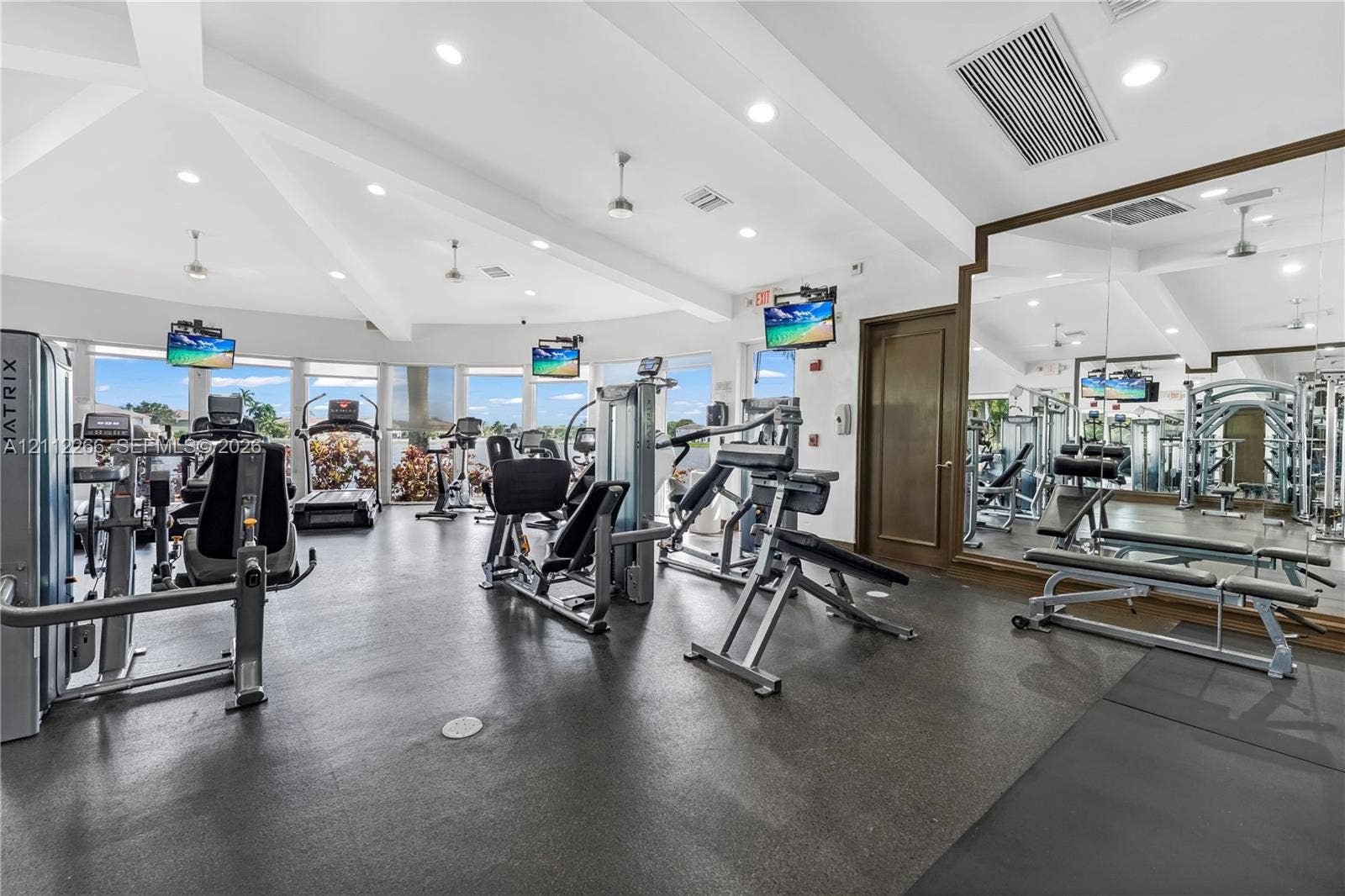 Fitness center featuring vaulted ceilings, floor-to-ceiling windows, full-wall mirrors, recessed lighting, and rubberized flooring