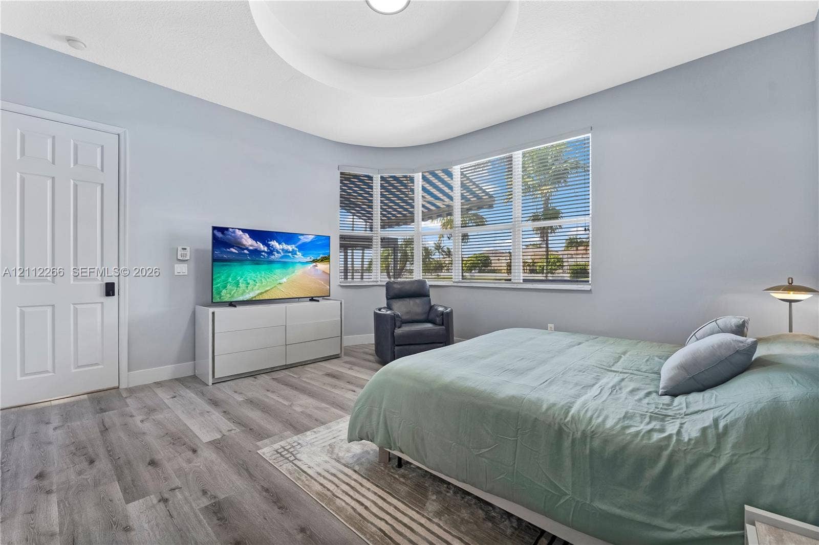 Tray ceiling featuring a recessed circular design, wood-finish flooring, and expansive bay windows