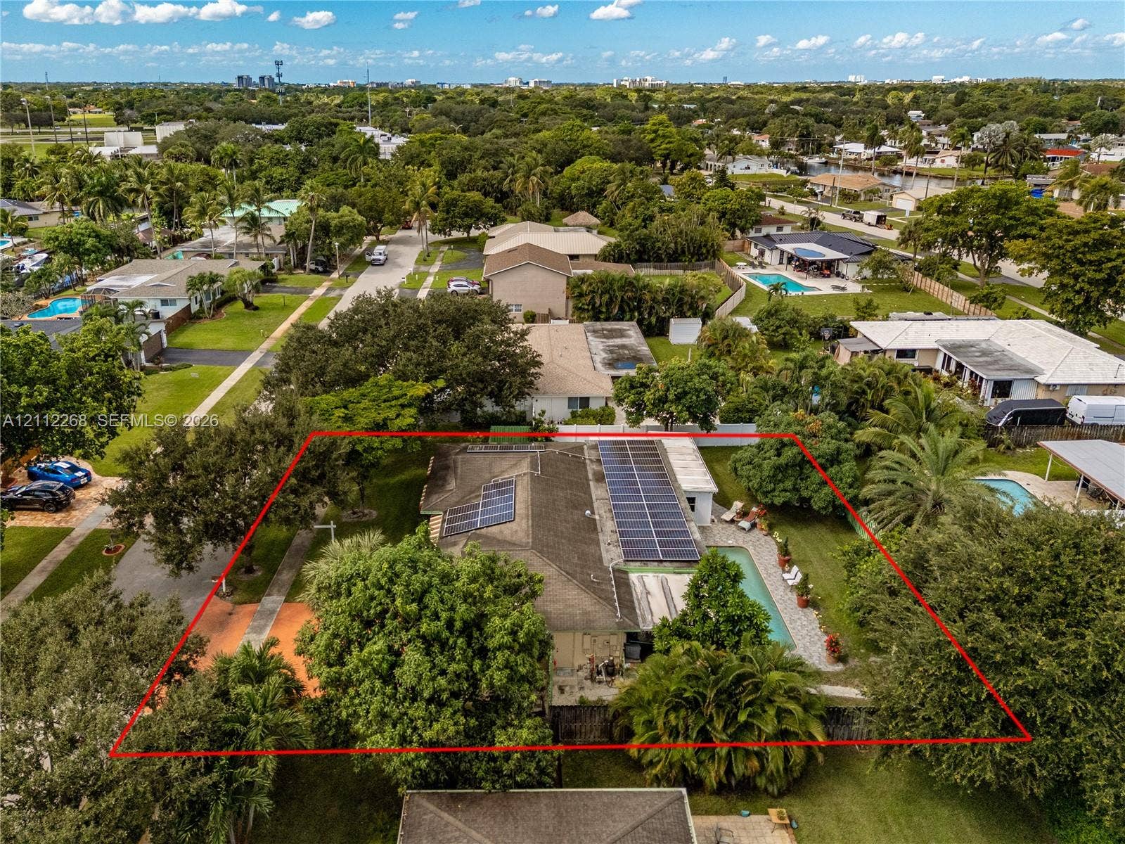 5941 SW 16th Court, Plantation, FL 33317 Aerial perspective of a property featuring roof-mounted solar panels, an in-ground swimming pool, and mature landscaping