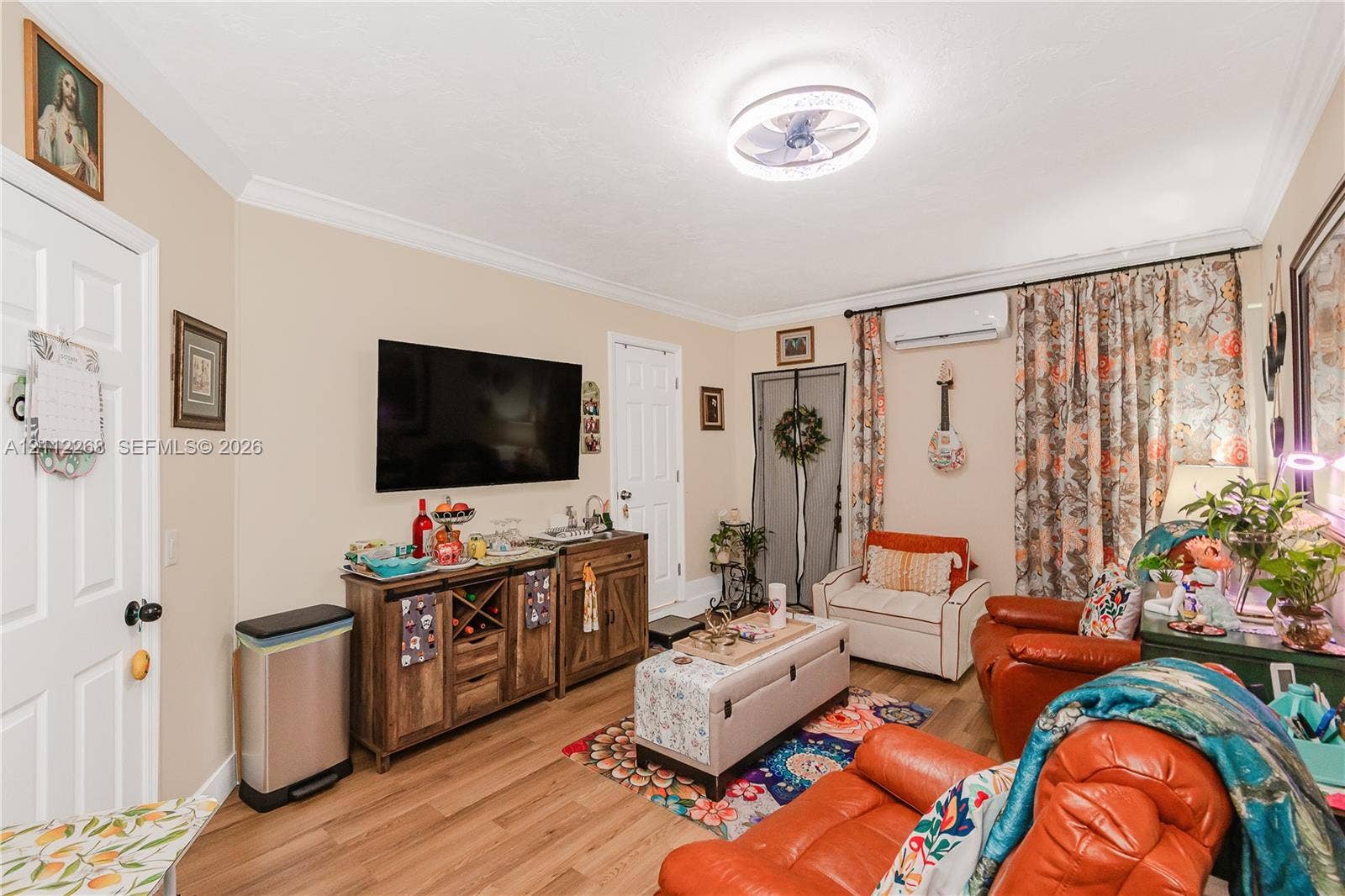 5941 SW 16th Court, Plantation, FL 33317 Living area featuring crown molding, wood-finish flooring, a wall-mounted ductless air conditioning unit, and a flush-mount circular LED ceiling light fixture