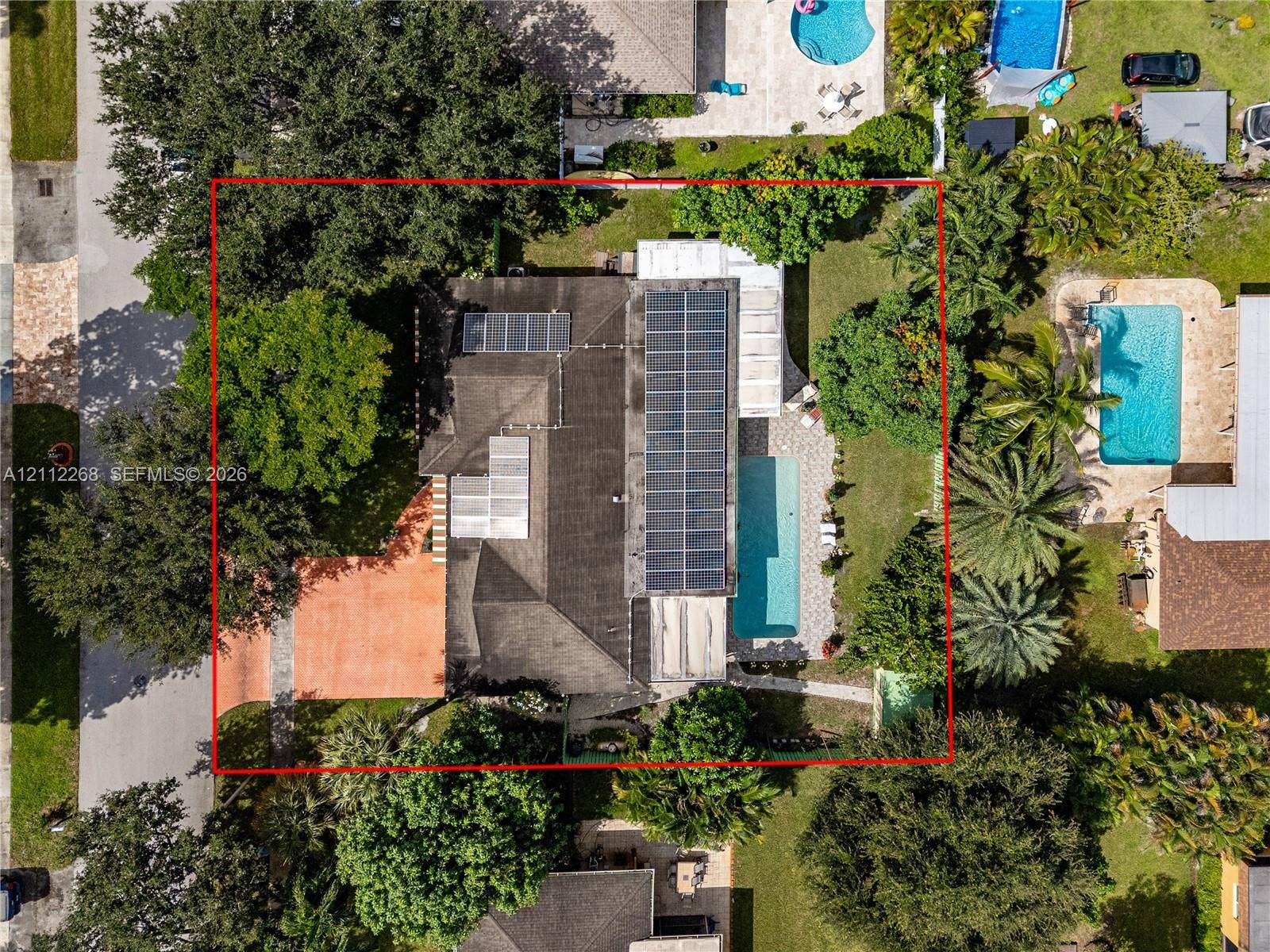 5941 SW 16th Court, Plantation, FL 33317 Aerial perspective of a property featuring solar panels, a rectangular swimming pool, a paved patio area, and mature landscaping