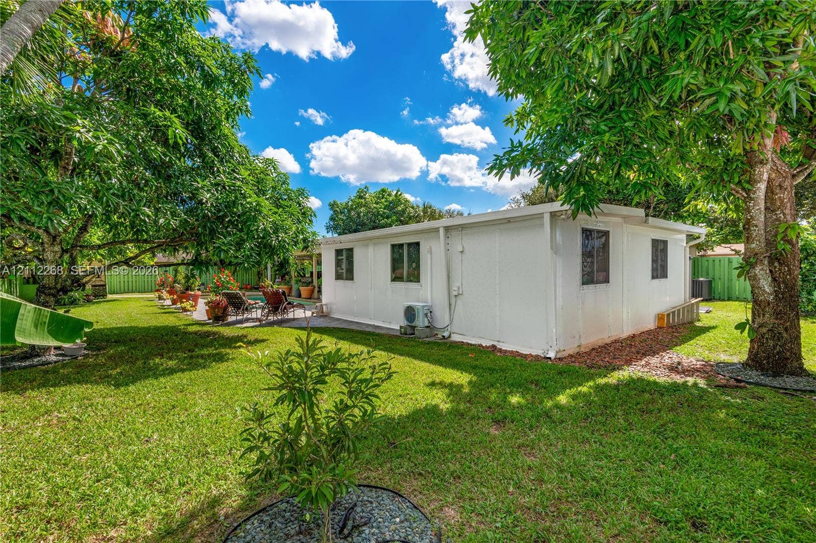 5941 SW 16th Court, Plantation, FL 33317 Expansive backyard featuring a lush lawn, mature shade trees, and a perimeter privacy fence