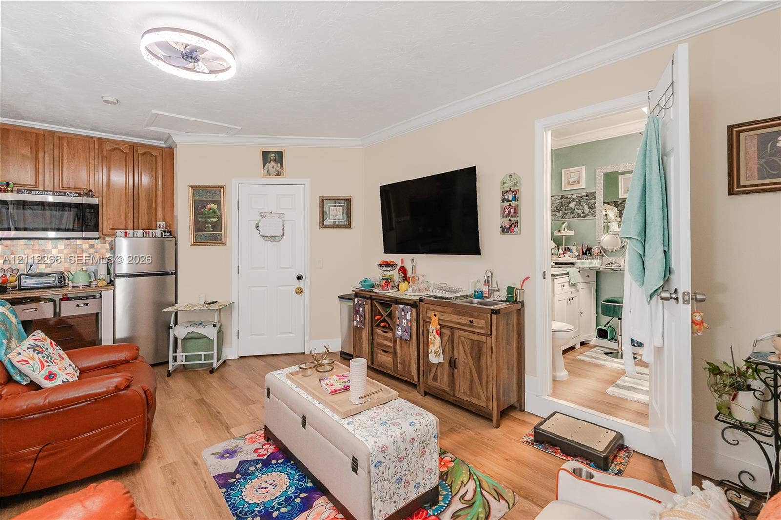5941 SW 16th Court, Plantation, FL 33317 Kitchenette featuring wood-finish cabinetry, stainless steel microwave, and integrated tiled backsplash, complemented by wood-finish flooring and crown molding