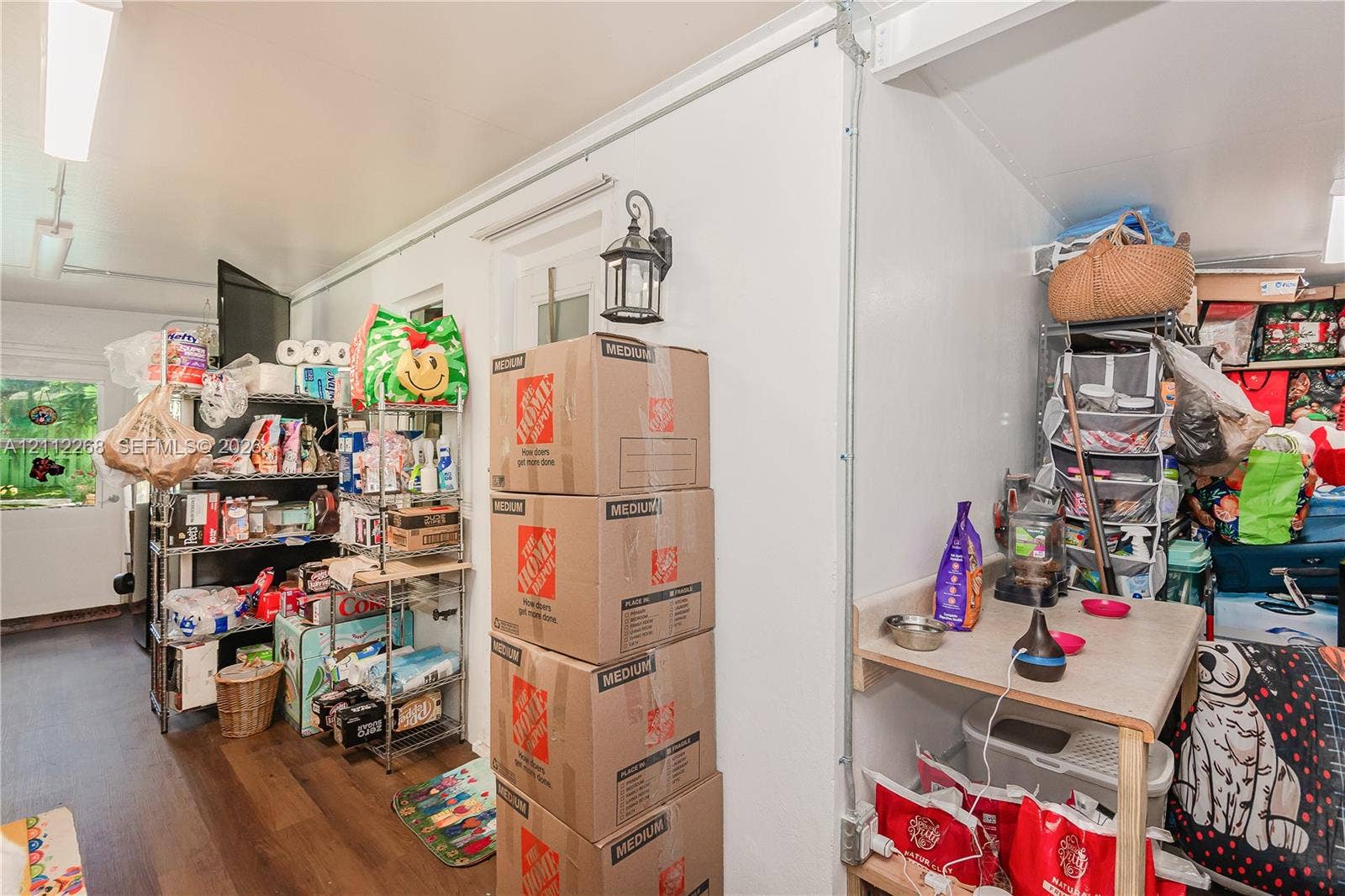 5941 SW 16th Court, Plantation, FL 33317 Interior space featuring wood-finish flooring, white walls, industrial-style exposed electrical conduit, and an exterior-grade wall-mounted lantern