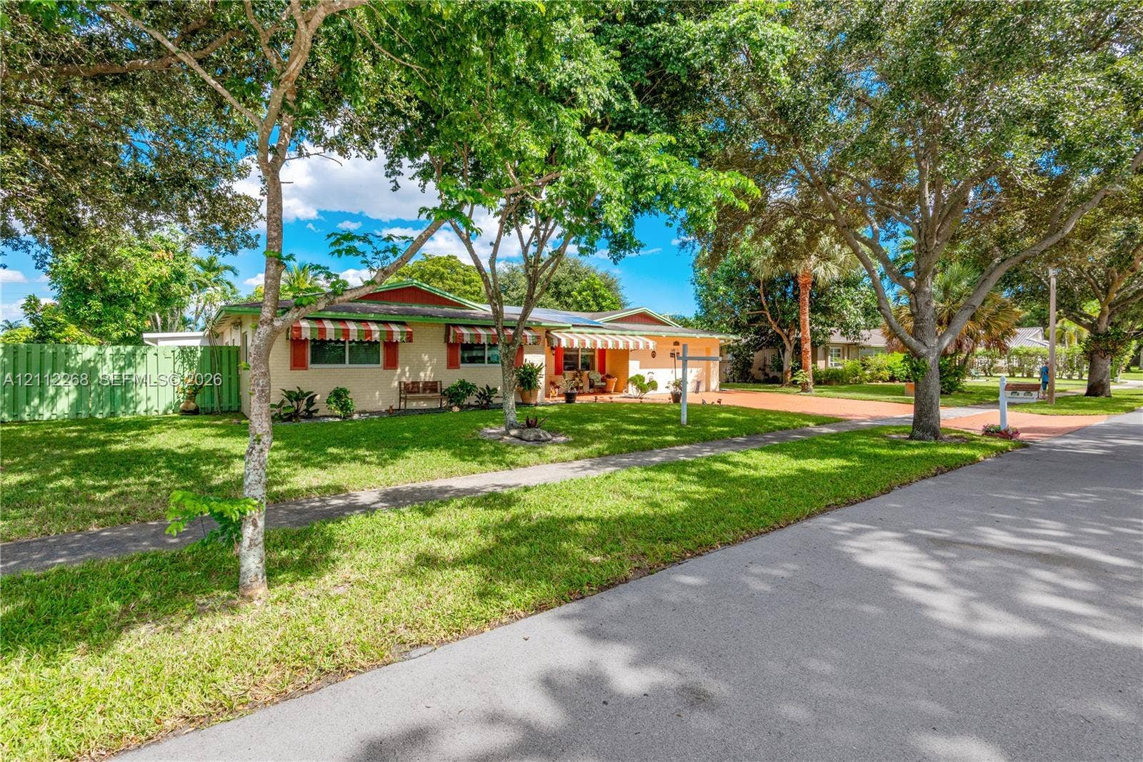 5941 SW 16th Court, Plantation, FL 33317 Single-story residence featuring a low-pitch roofline, integrated window awnings, a paved driveway, and mature landscaping within a grassy front yard
