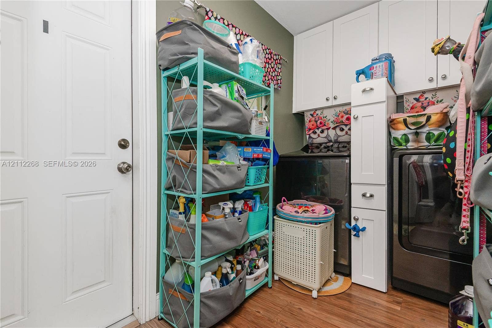 5941 SW 16th Court, Plantation, FL 33317 Laundry area featuring white shaker-style wall cabinets, a tall narrow storage tower with drawers, and wood-finish flooring