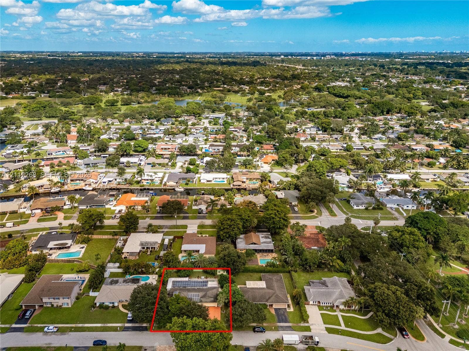 5941 SW 16th Court, Plantation, FL 33317 Aerial perspective of a residential property featuring a prominent roof-mounted solar array, mature perimeter landscaping, and an expansive rear lawn