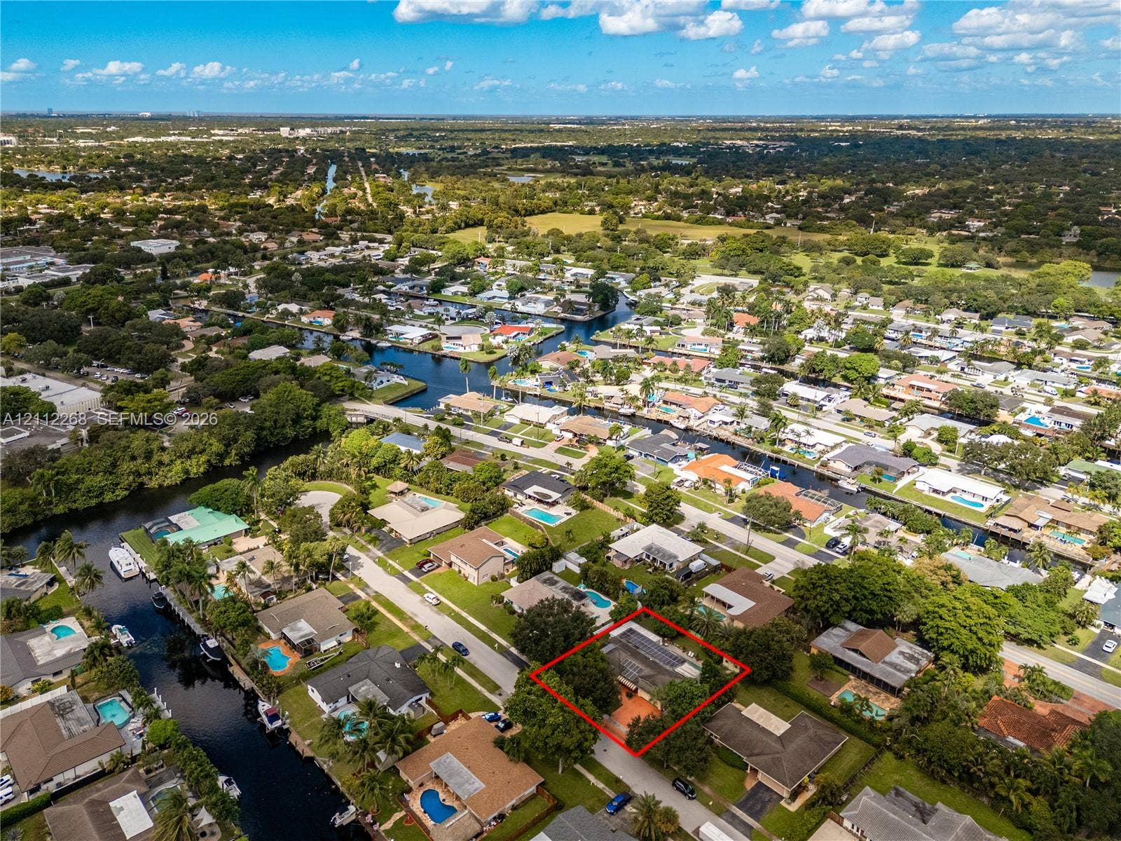 5941 SW 16th Court, Plantation, FL 33317 Aerial perspective of a single-story residence featuring a shingled roof, attached garage, and mature landscaping situated in a canal-front neighborhood