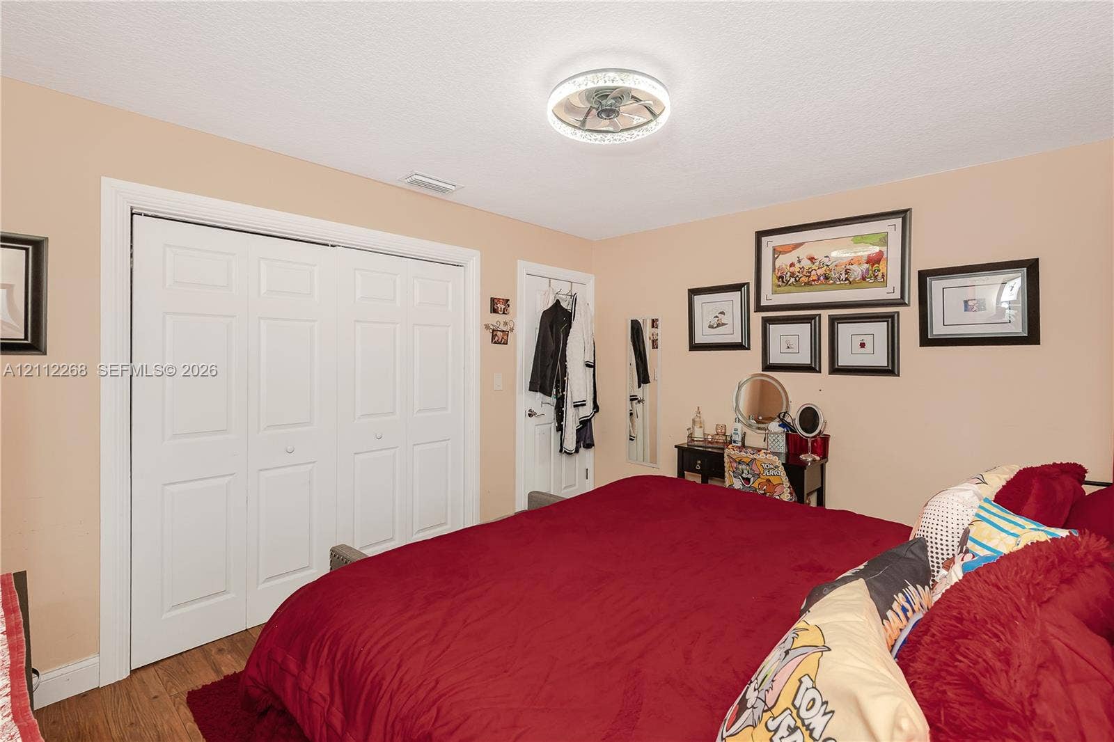 5941 SW 16th Court, Plantation, FL 33317 Bedroom featuring wood-finish flooring, a ceiling-mounted light fixture with a decorative rim, and bi-fold closet doors