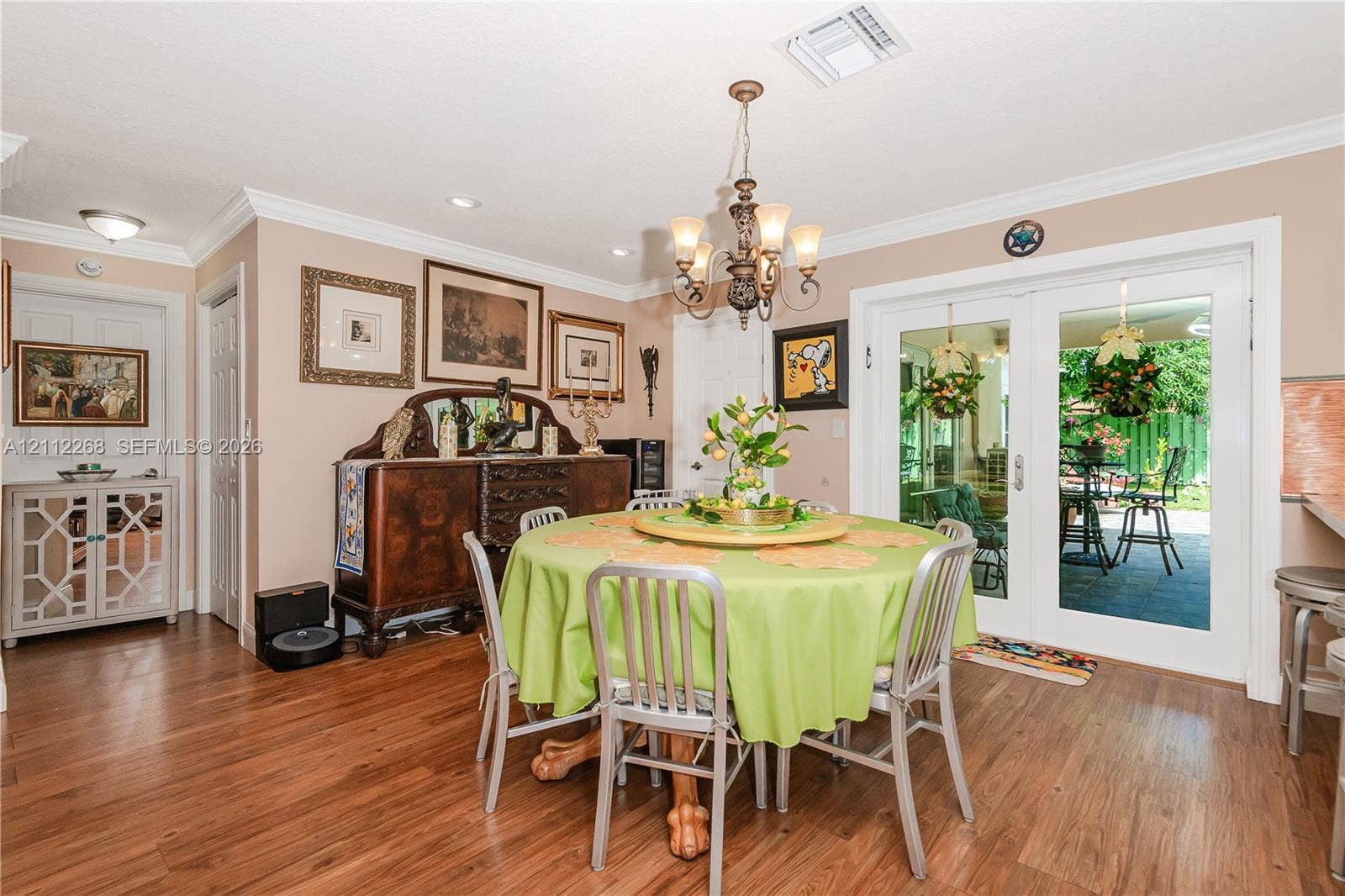 5941 SW 16th Court, Plantation, FL 33317 Dining area featuring wood-finish flooring, a decorative multi-arm chandelier, crown molding, and double-pane glass doors