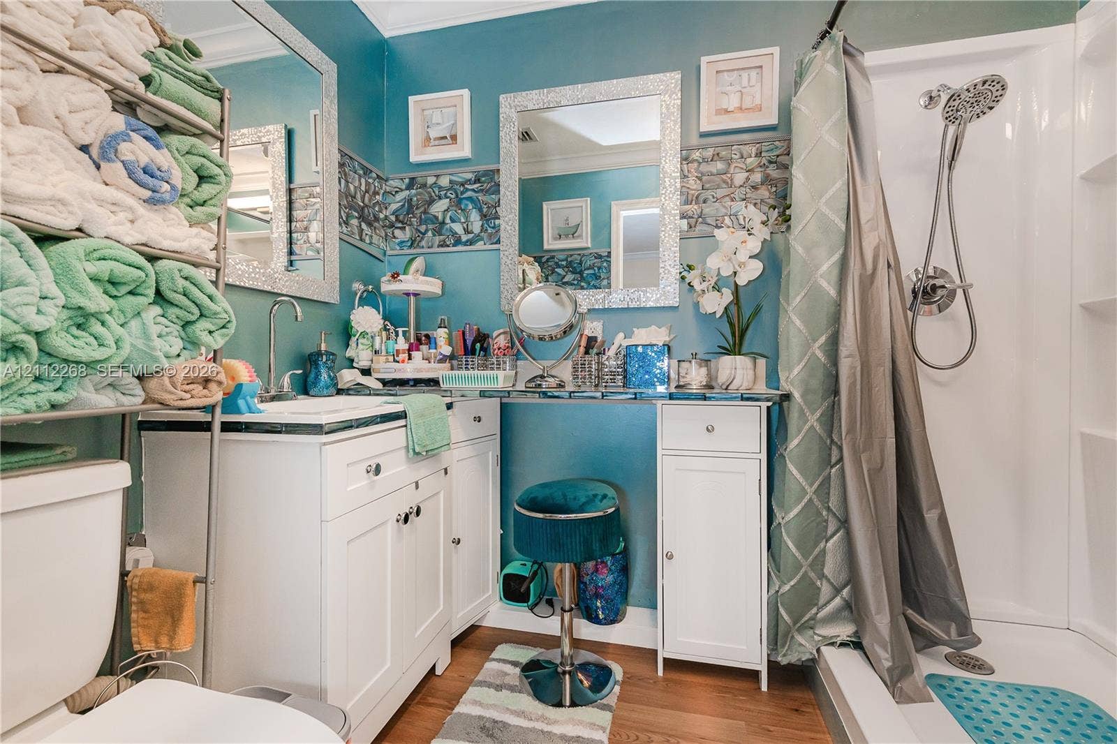 5941 SW 16th Court, Plantation, FL 33317 White vanity with integrated storage, decorative stone-tile backsplash, wall-mounted mirror with mosaic-style frame, and shower unit with handheld fixture