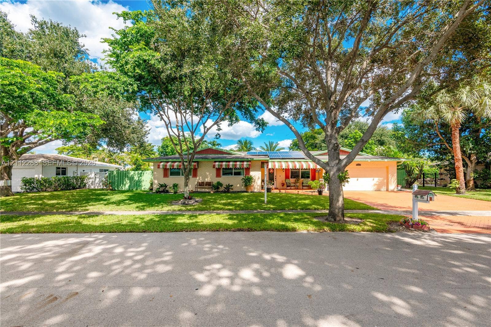 5941 SW 16th Court, Plantation, FL 33317 Single-story residence featuring a paved driveway, attached garage, solar panels, and mature landscaping