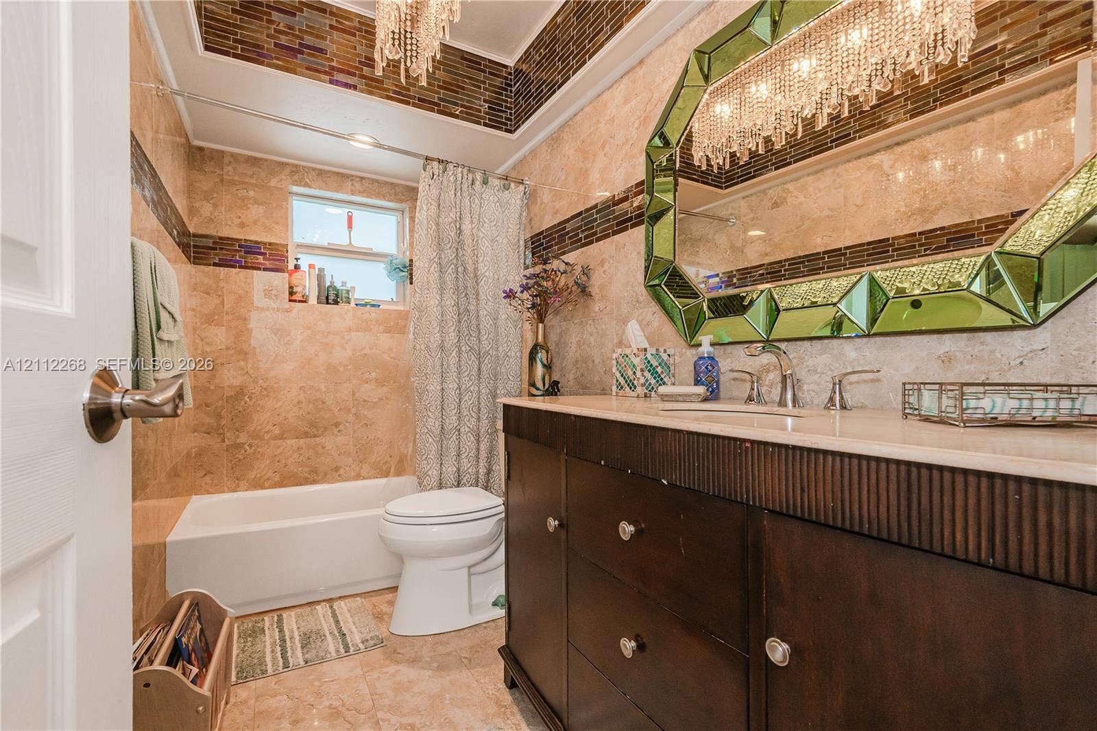 5941 SW 16th Court, Plantation, FL 33317 Bathroom featuring full-height wall tiling with decorative glass mosaic inlay, custom dark wood vanity with a solid surface countertop, and oversized framed mirror