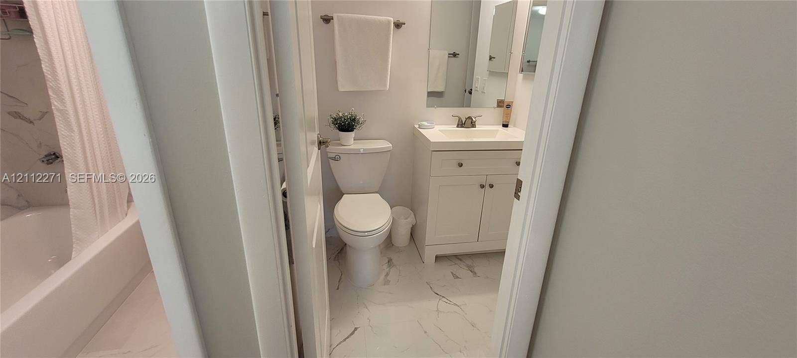 Bathroom featuring a vanity with shaker-style cabinetry, white integrated countertop, and wall-mounted mirror