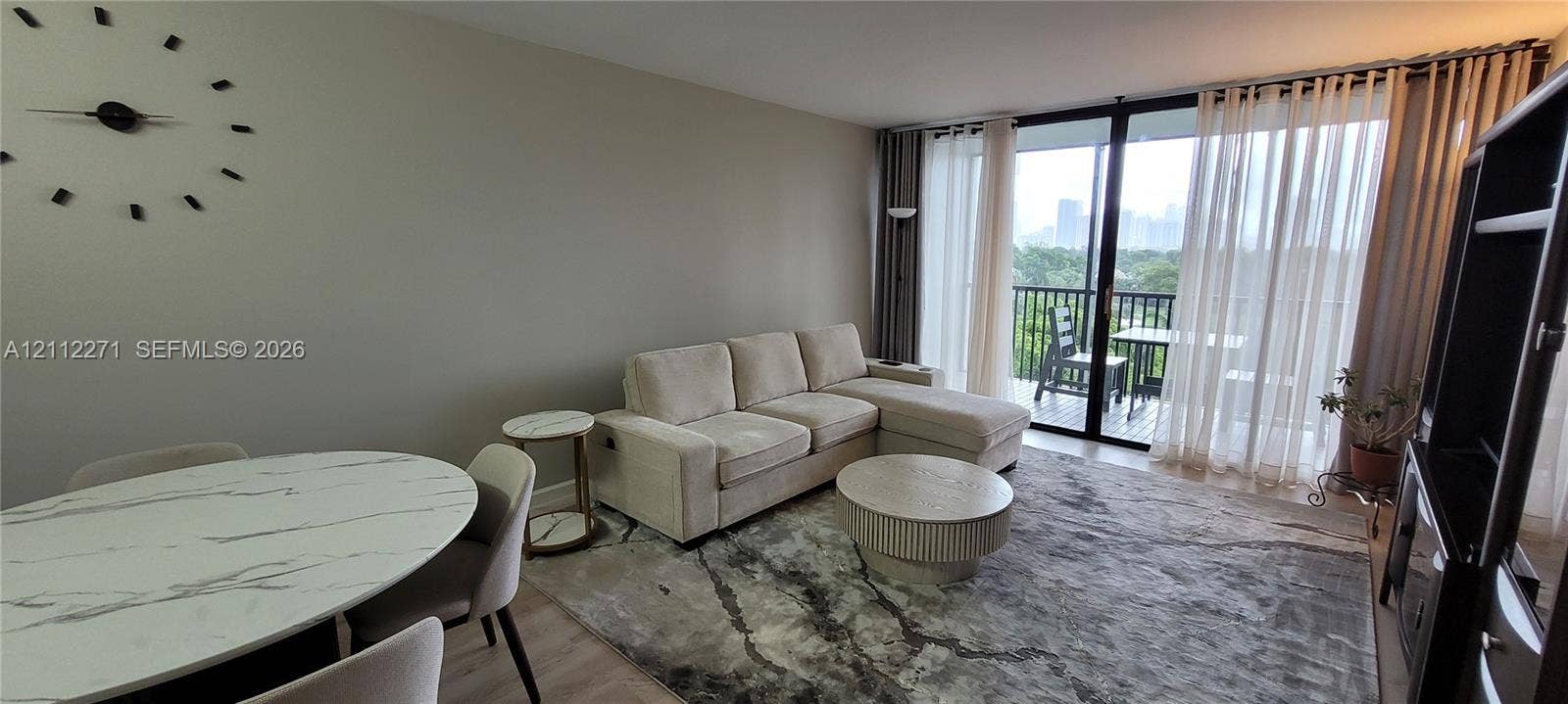 Open-concept living space featuring wood-finish flooring and floor-to-ceiling sliding glass doors opening to an exterior balcony