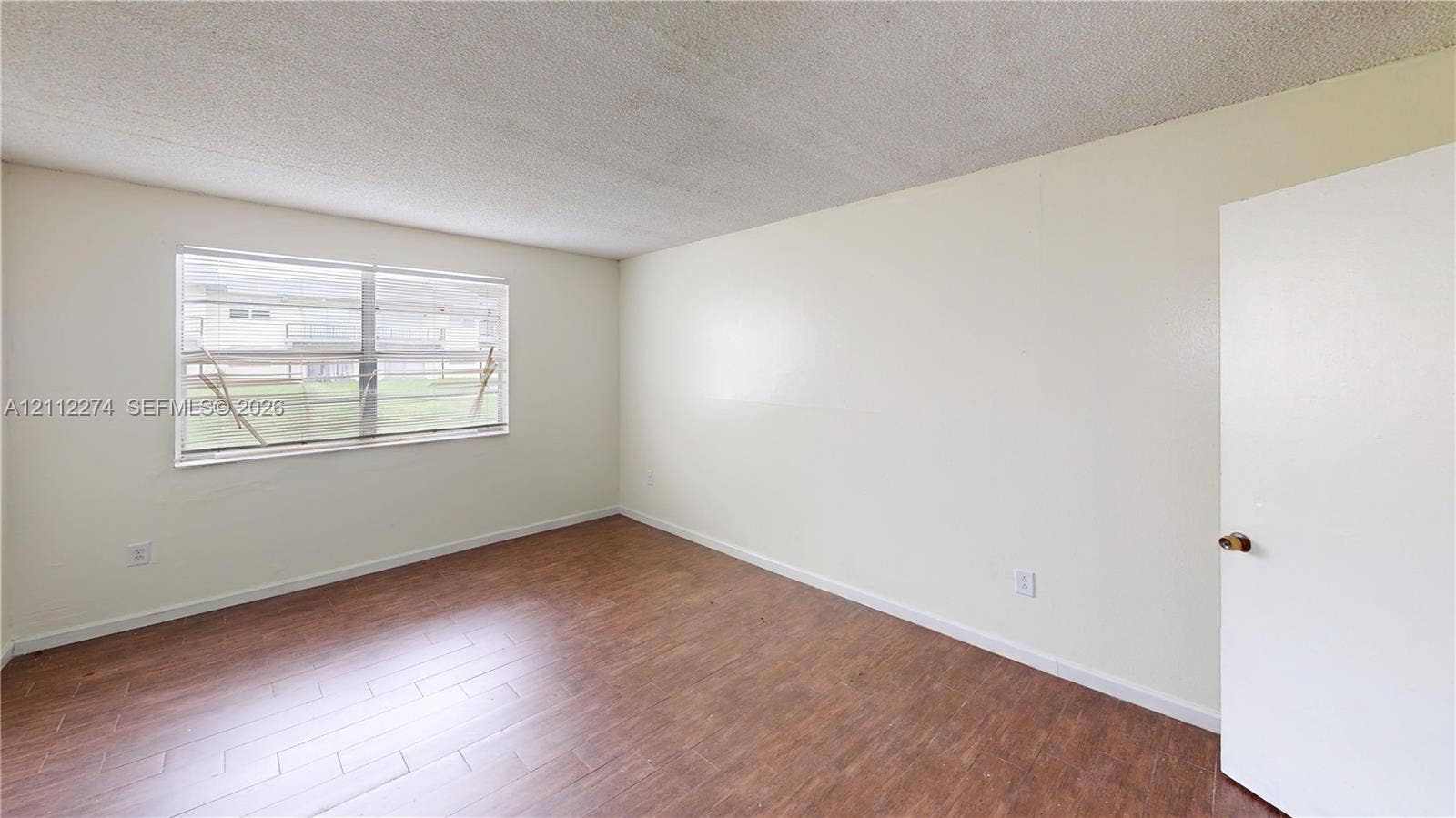 301 NW 177th Street, #141, Miami Gardens, FL 33169 Room interior featuring wood-finish flooring, neutral wall paint, and a single-pane horizontal window
