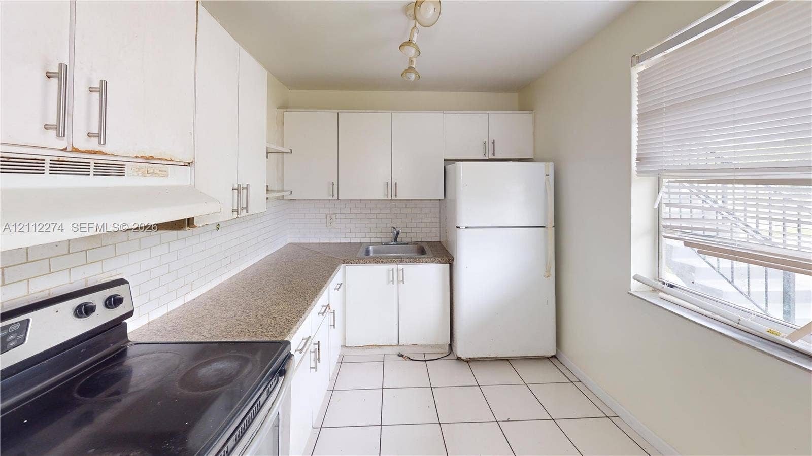 301 NW 177th Street, #141, Miami Gardens, FL 33169 Kitchen featuring white cabinetry, solid surface countertops, a white tile backsplash, ceramic tile flooring, and integrated white appliances