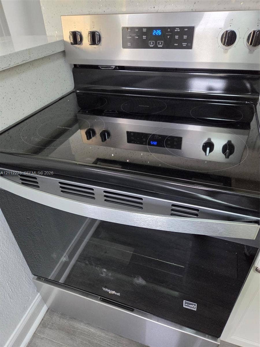 Stainless steel freestanding electric range with a glass cooktop, digital control panel, and full-width oven handle