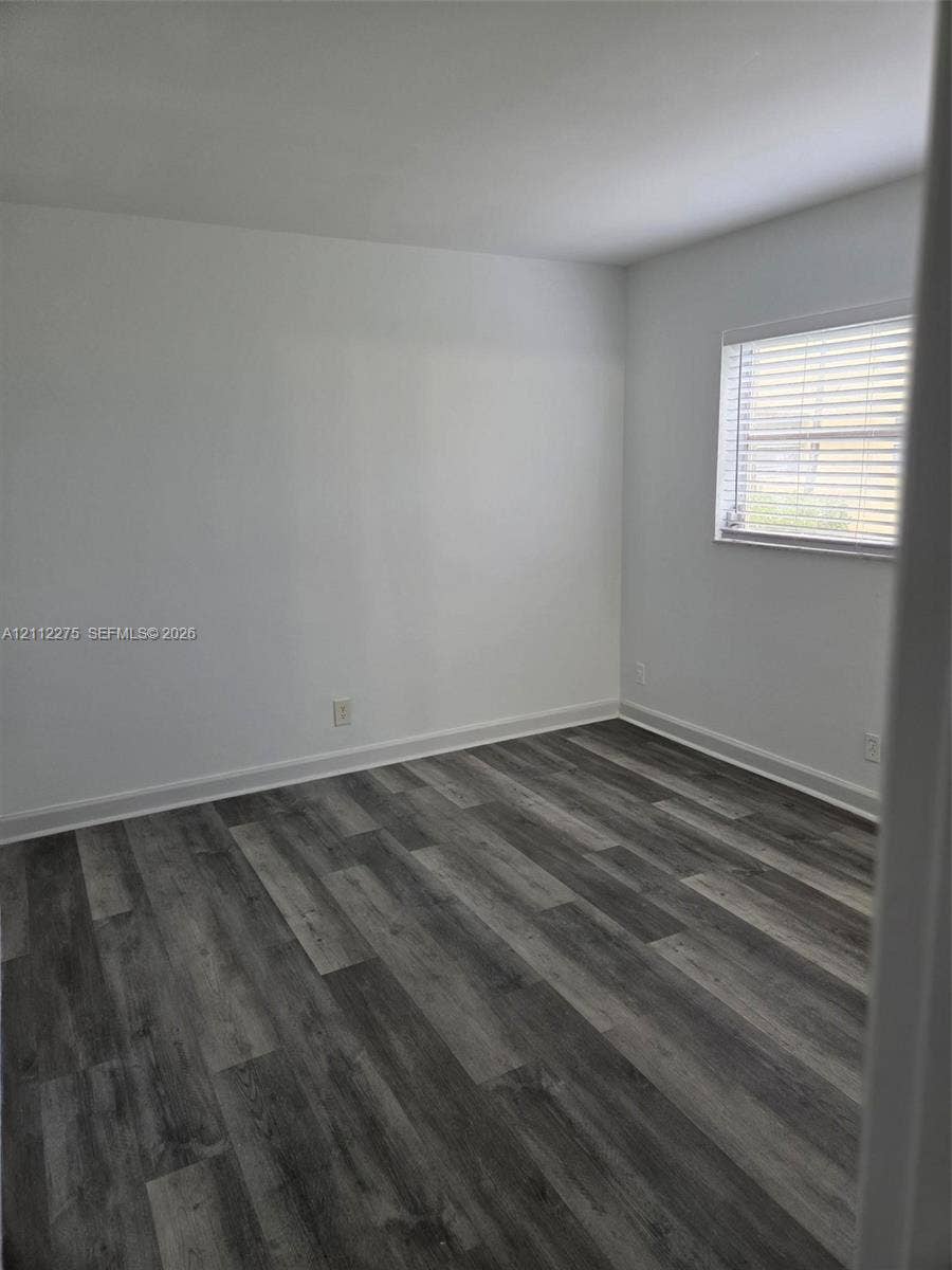 Neutral interior featuring wood-finish flooring and a window with horizontal blinds