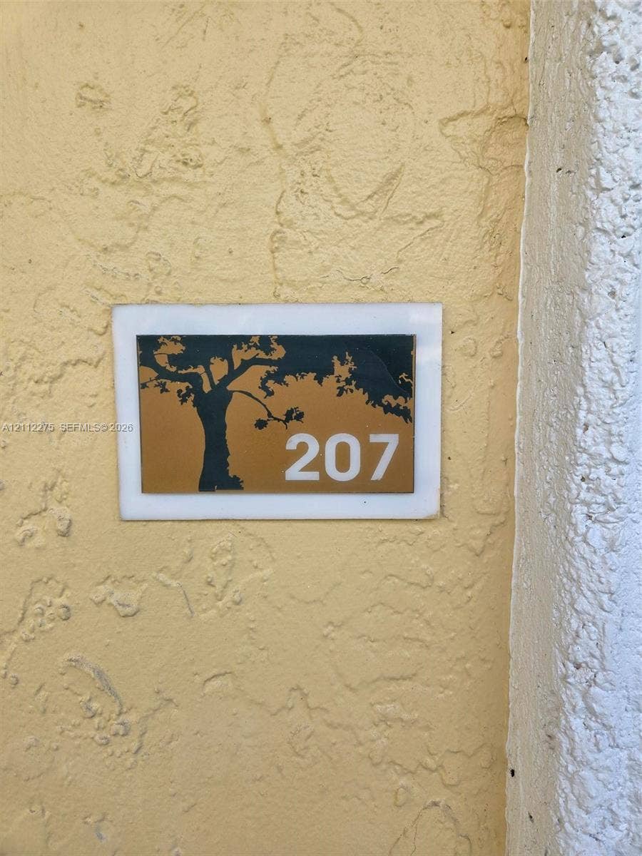 Custom wall-mounted address plaque featuring a tree silhouette graphic and numeric identification on a textured stucco exterior wall