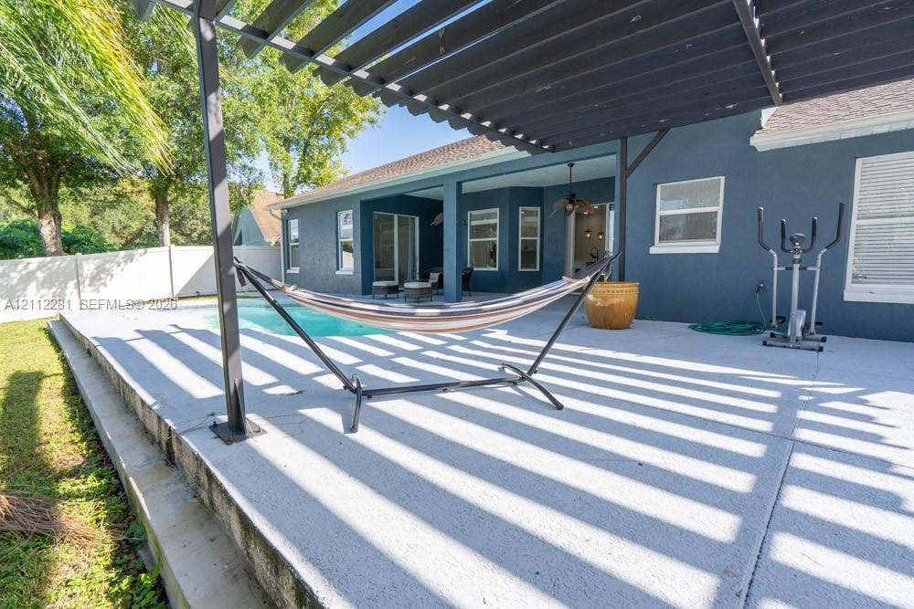 2461 Winfield, Kissimmee, FL 34743 Covered concrete patio featuring a dark-toned pergola, built-in swimming pool, and white perimeter privacy fencing