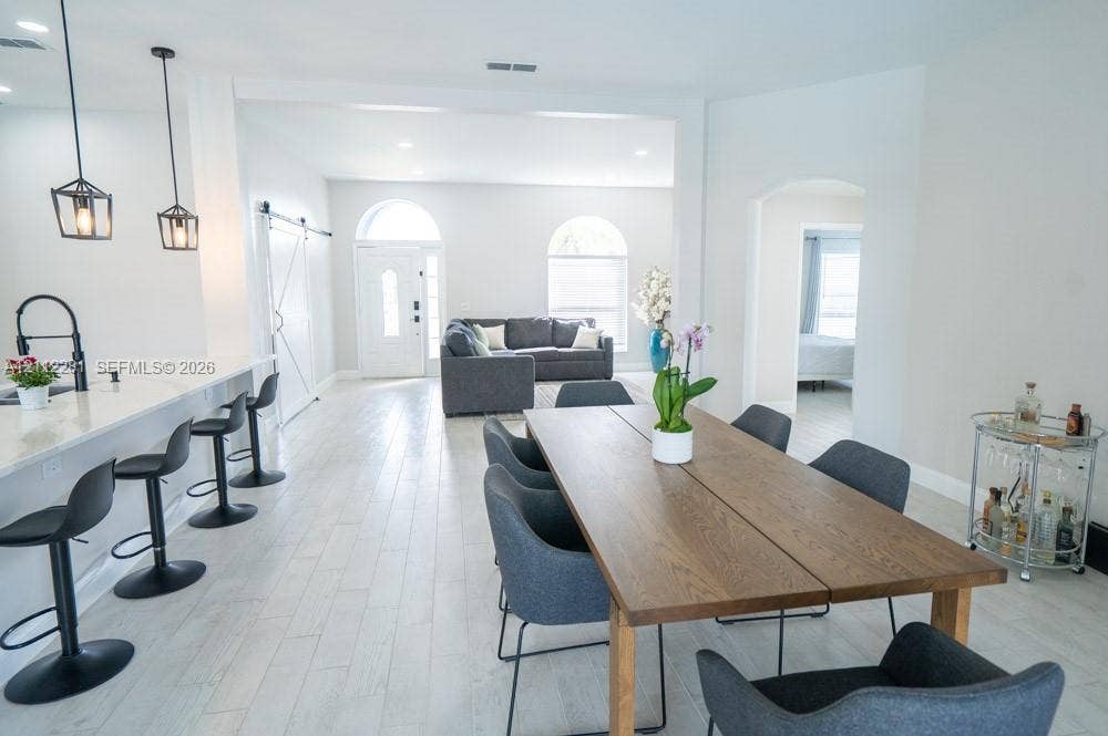 2461 Winfield, Kissimmee, FL 34743 Open-concept interior featuring wood-finish flooring, breakfast bar with pendant lighting, arched windows, and a sliding barn-style door