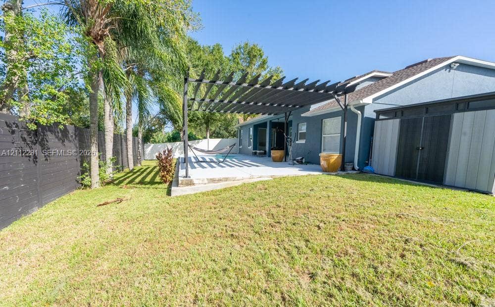 2461 Winfield, Kissimmee, FL 34743 Backyard featuring a concrete patio, black metal pergola, horizontal slat fencing, and mature palm trees