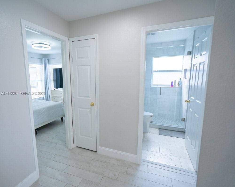 2461 Winfield, Kissimmee, FL 34743 Hallway featuring wood-finish flooring, white panel doors, and entry into a bathroom with tile surround shower