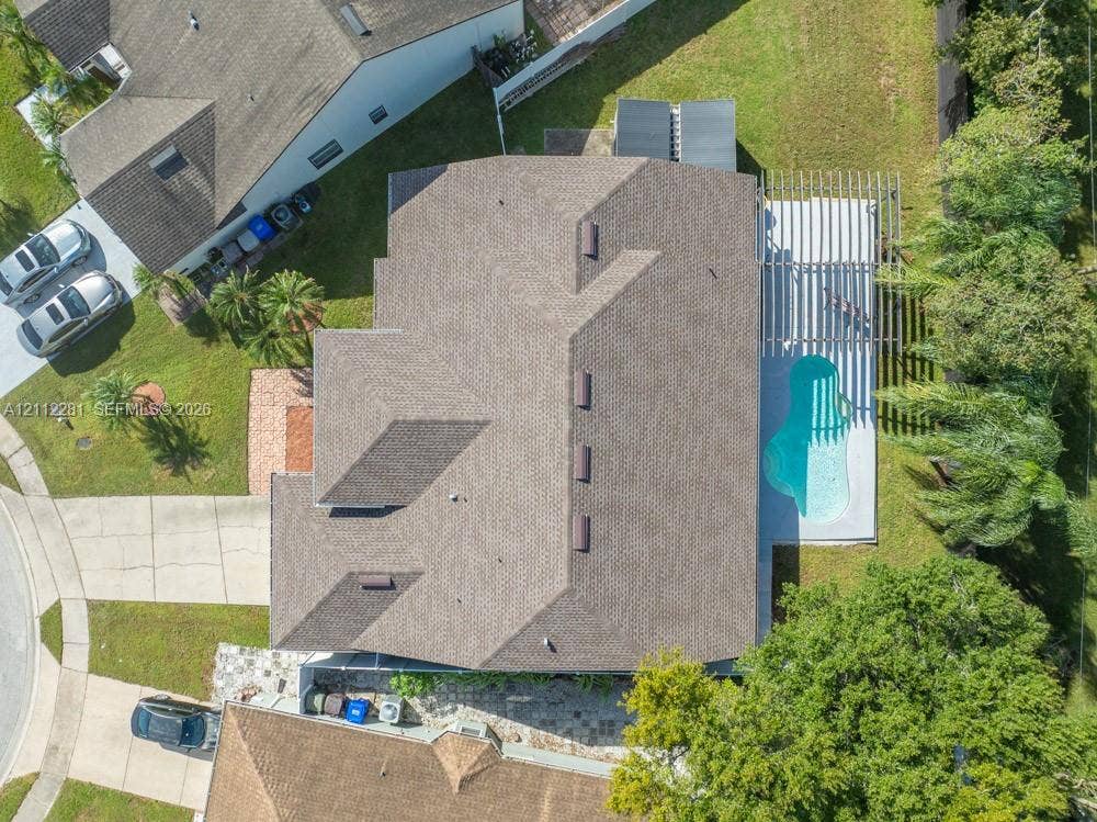 2461 Winfield, Kissimmee, FL 34743 Aerial view of property featuring a shingled roof, a backyard swimming pool, a patio pergola, and mature landscaping