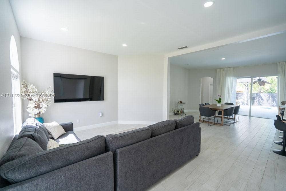 2461 Winfield, Kissimmee, FL 34743 Open-concept interior featuring light-toned tile flooring, recessed ceiling lighting, arched wall detailing, and glass sliding doors