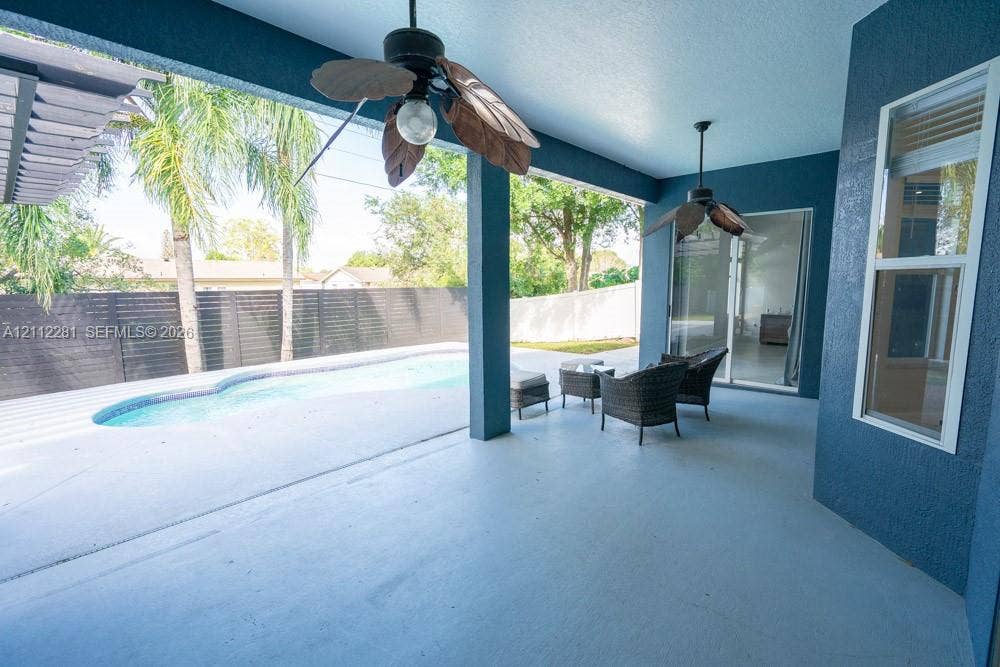 2461 Winfield, Kissimmee, FL 34743 Covered patio featuring two ceiling fans, painted exterior wall finish, and direct access to an in-ground swimming pool enclosed by privacy fencing