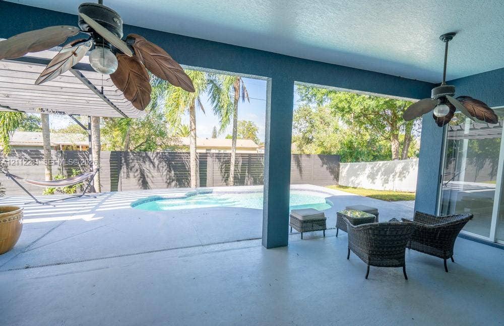 2461 Winfield, Kissimmee, FL 34743 Covered patio featuring two ceiling fans, painted concrete flooring, and an in-ground swimming pool with a privacy fence
