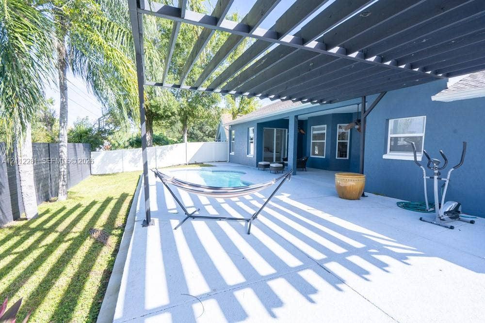 2461 Winfield, Kissimmee, FL 34743 Outdoor patio featuring a dark metal pergola, concrete flooring, in-ground swimming pool, and white perimeter privacy fencing