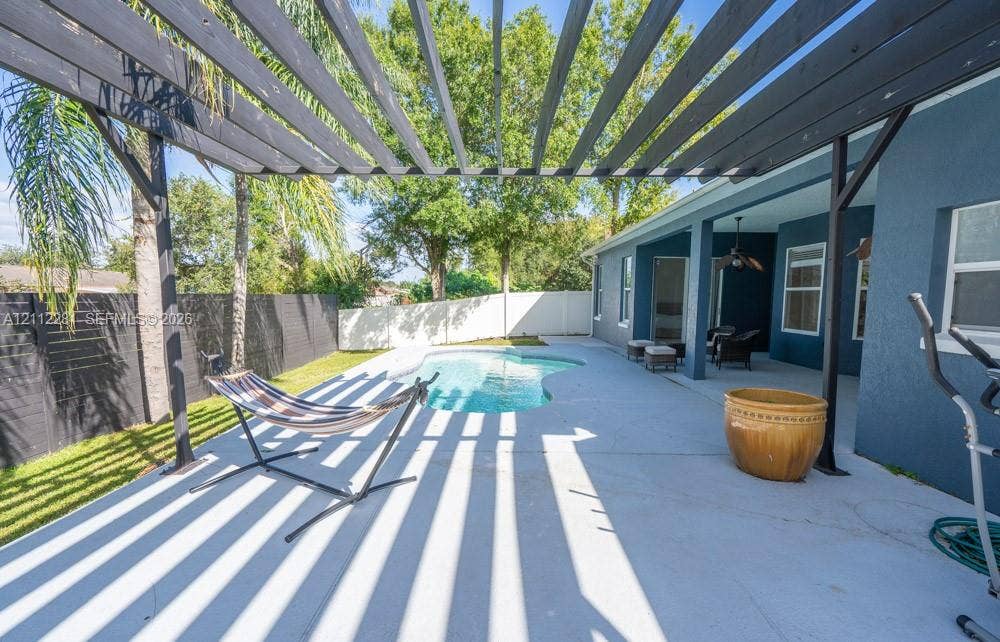 2461 Winfield, Kissimmee, FL 34743 Covered patio with a custom wood-beam pergola, swimming pool, concrete hardscaping, and perimeter fencing