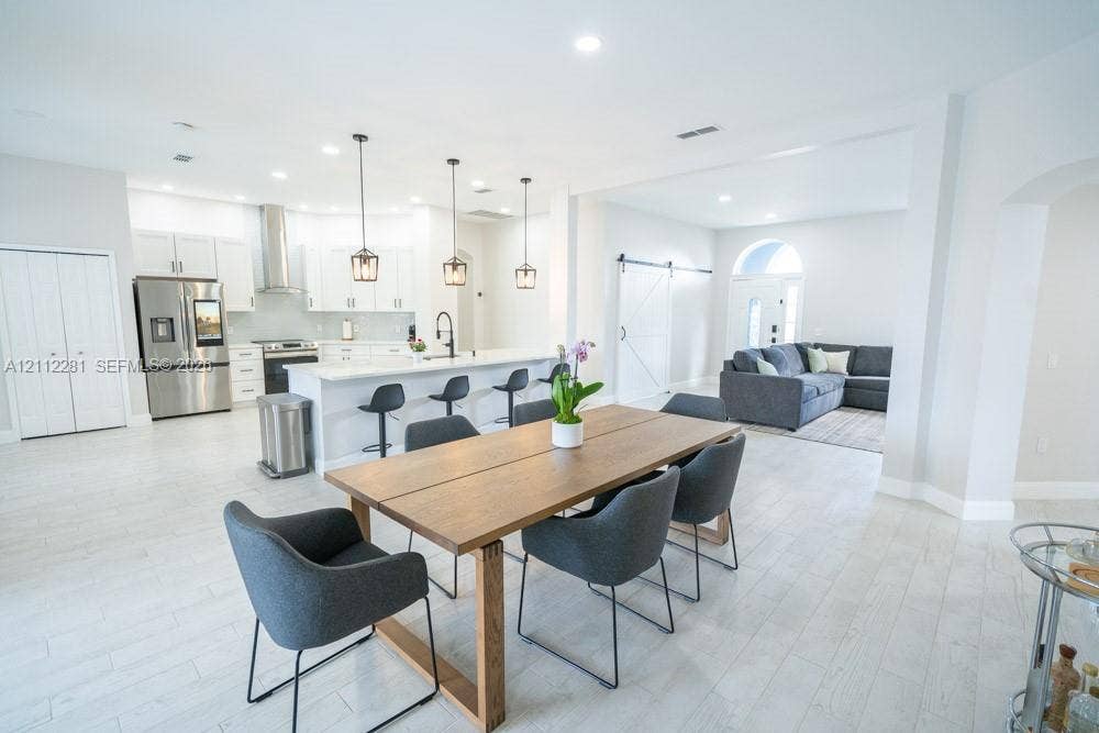 2461 Winfield, Kissimmee, FL 34743 Open-concept kitchen featuring shaker-style cabinetry, quartz countertops, a stainless steel chimney-style range hood, pendant lighting, and wood-finish tile flooring
