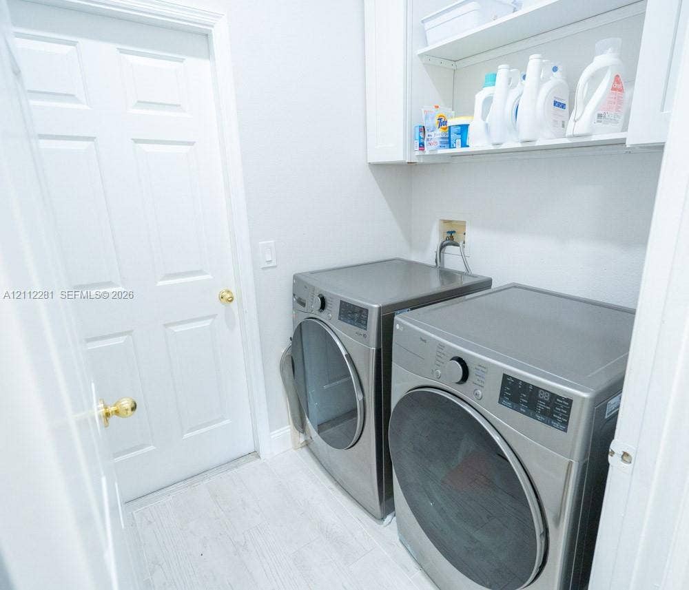 2461 Winfield, Kissimmee, FL 34743 Dedicated utility space featuring white built-in cabinetry, upper shelving, and white tile flooring